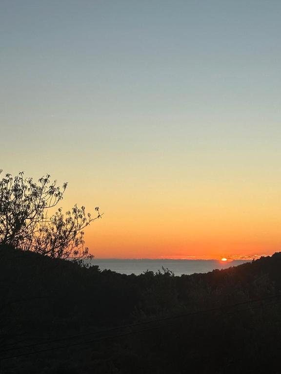 a sunset with the sun setting over the ocean at Desa's place in Babino Polje