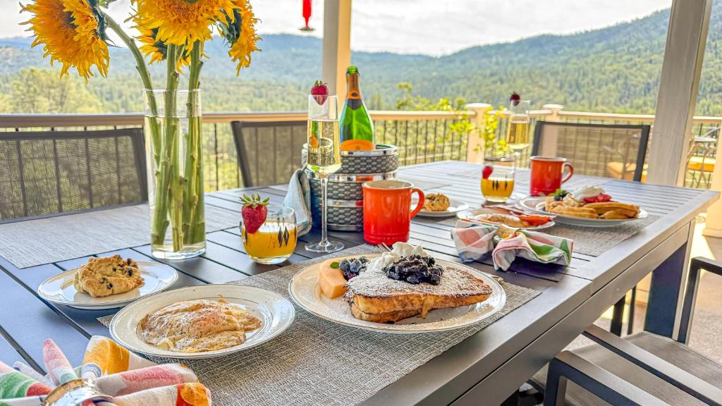 a table with plates of breakfast food on it at Mountain Daddies Boutique Bed & Breakfast near Yosemite - Fresh Homemade Breakfast Included in Oakhurst