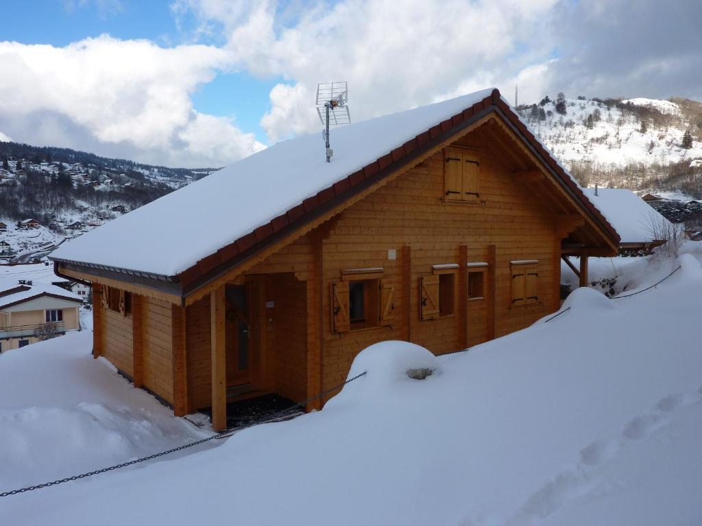 ラ・ブレスにあるLe Planotの屋根に雪が積もった丸太キャビン