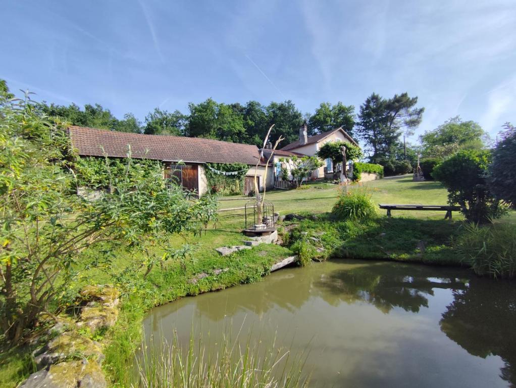 a house with a pond in front of it at Le Petit Gîte de L'Étang in Saint-Géry