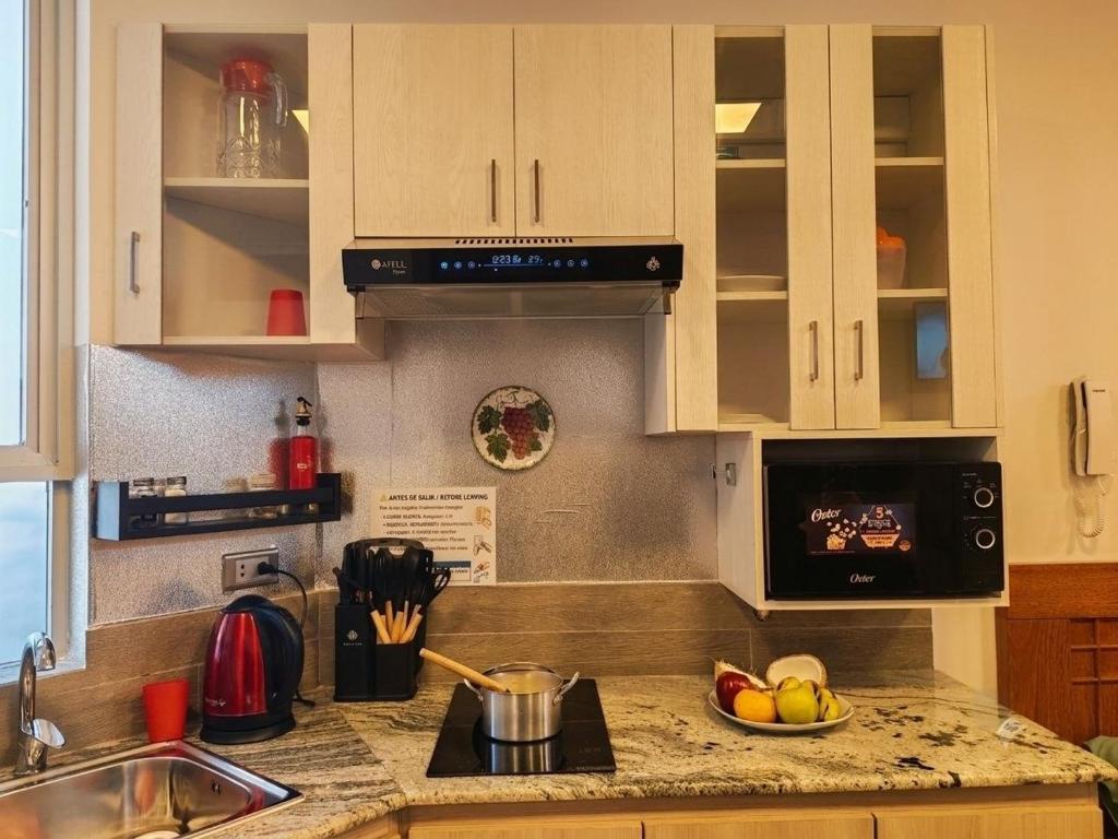a kitchen with white cabinets and a counter top with a sink at Loft de 2 Camas in Callampaya