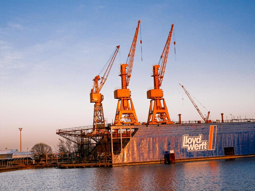 a large boat sitting in the water with cranes at Fischerhaus Bremerhaven in Bremerhaven