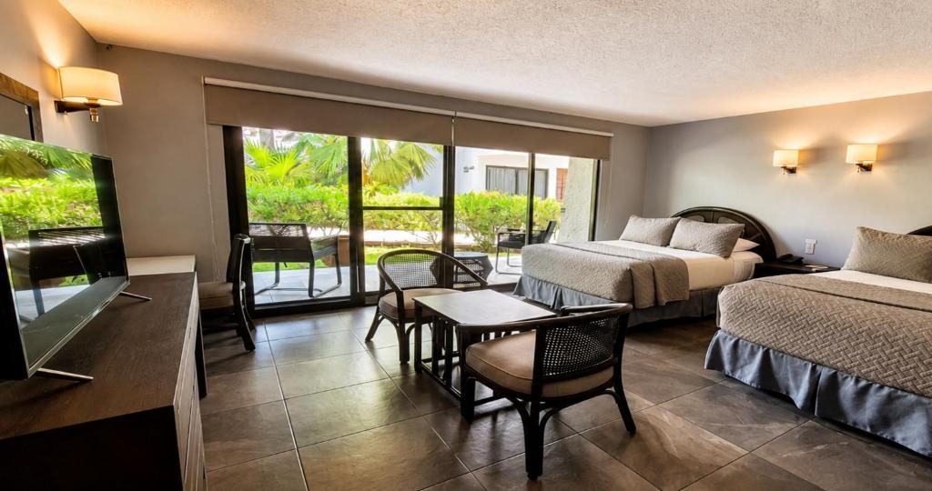 ein Hotelzimmer mit zwei Betten, einem Tisch und Stühlen in der Unterkunft Sina Suites Cancun - Adults Only in Cancún