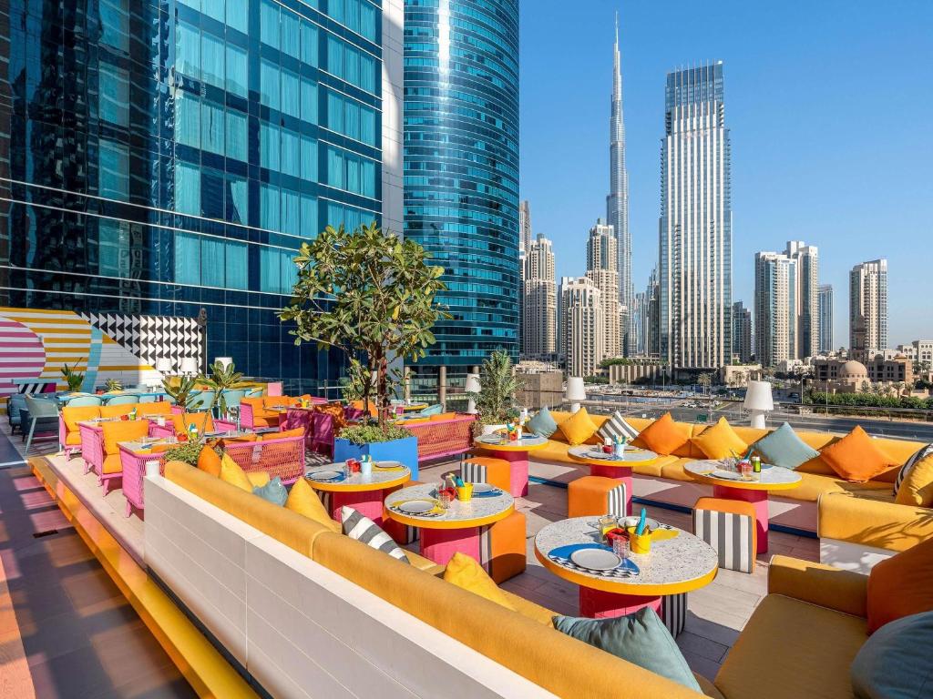 a rooftop patio with tables and chairs and a city skyline at Pullman Dubai Downtown in Dubai