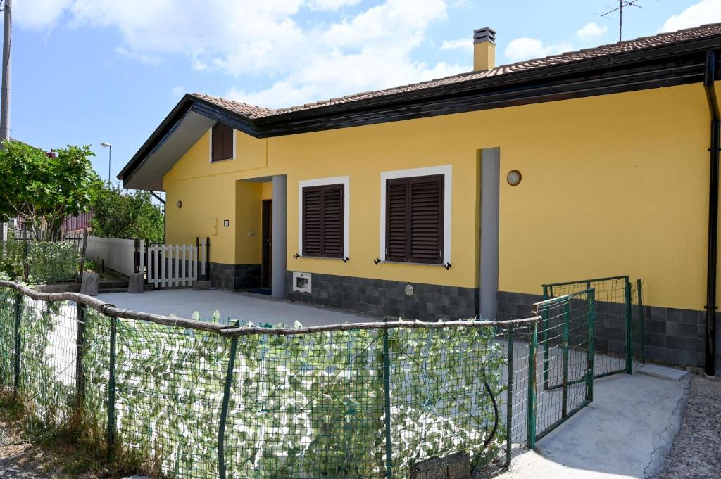 a yellow house with a fence in front of it at Casa Experience - Acri in Calamia