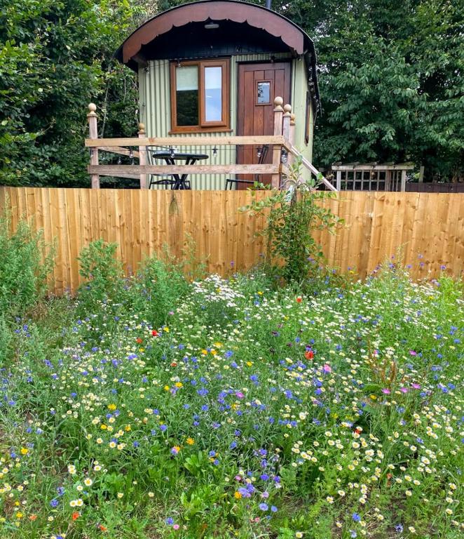 a small house with a fence and a field of flowers at The Willows in Scarisbrick