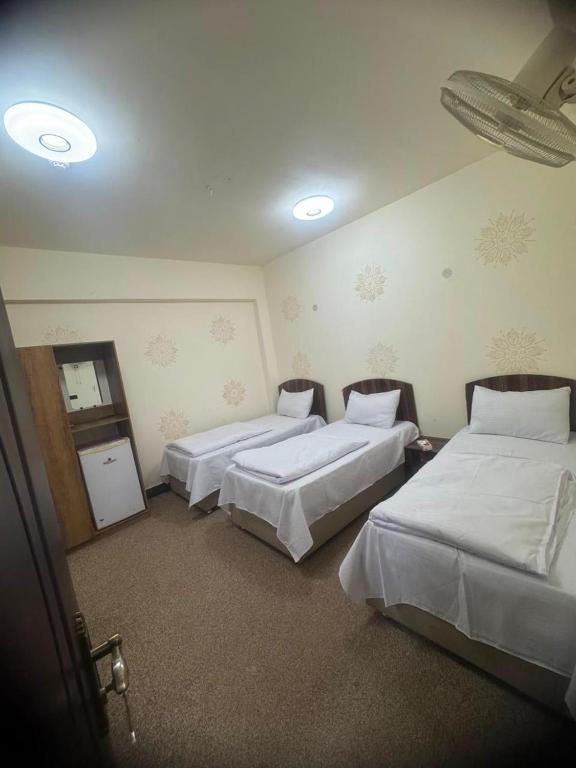 a hotel room with three beds in it at فندق ومطعم درة علي in Qaryatal Karkāshīyah