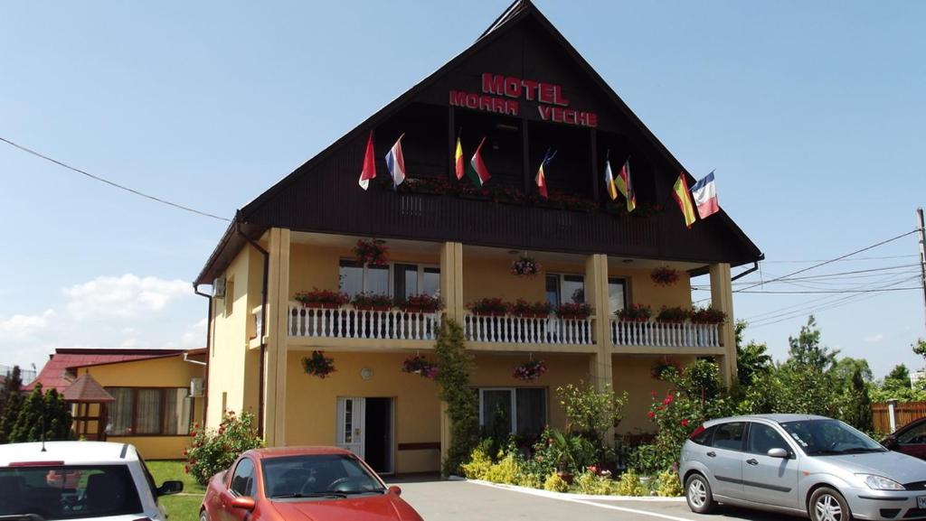a hotel with cars parked in a parking lot at Motel Moara Veche in Săcălăşeni