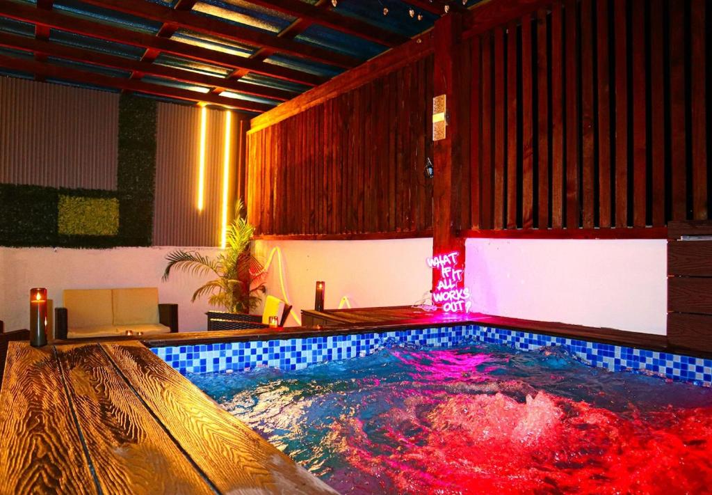 a large swimming pool in a room with a red light at Your Private Patio Oasis Spa Pool Lounge 2BR in Santiago de los Caballeros