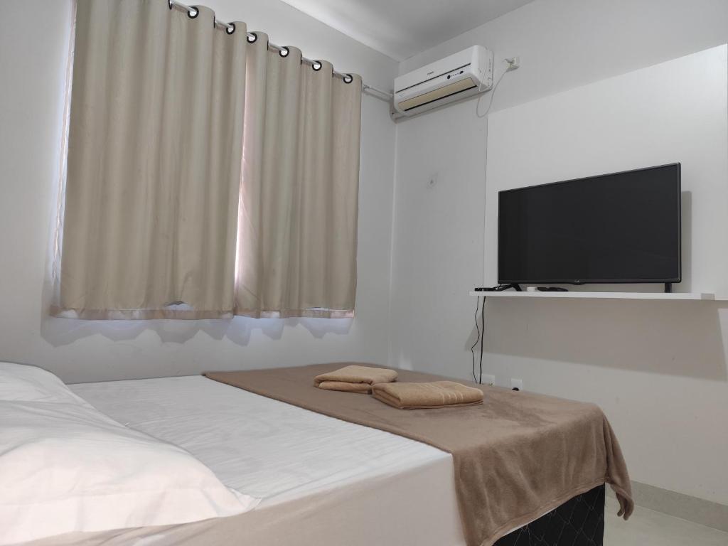 a bedroom with a bed and a flat screen tv at apartment work centro in Ubá