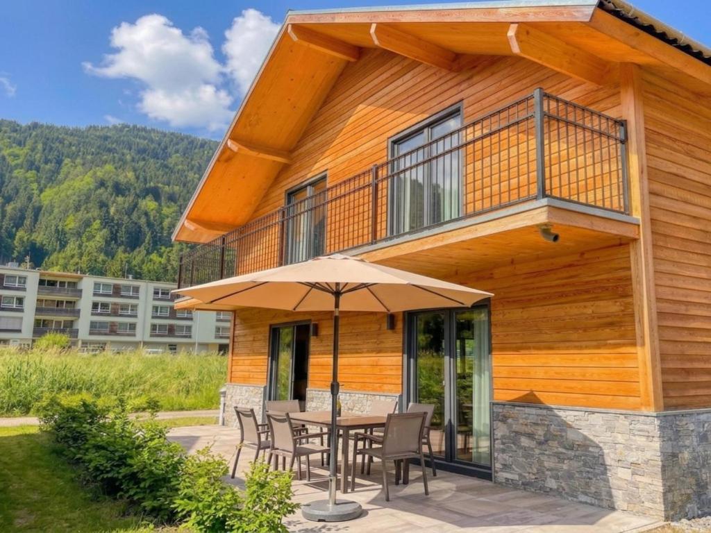a house with a table and chairs and an umbrella at Seeperle in Afritz