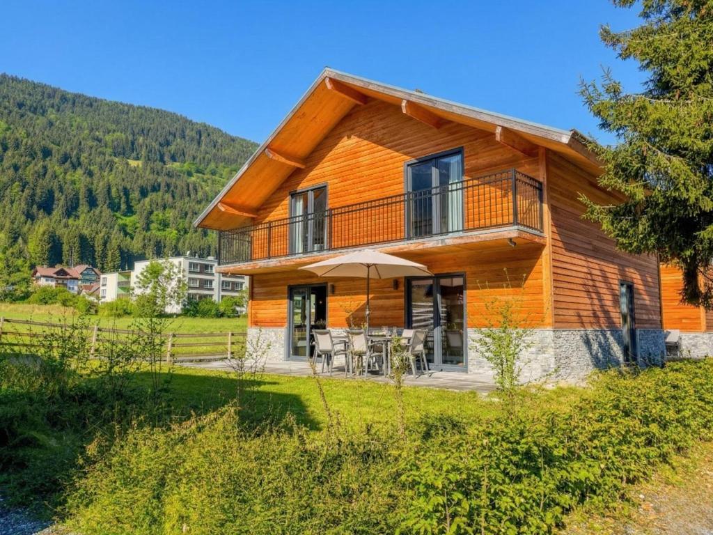 a log house with a balcony and an umbrella at am Afritzer See in Afritz