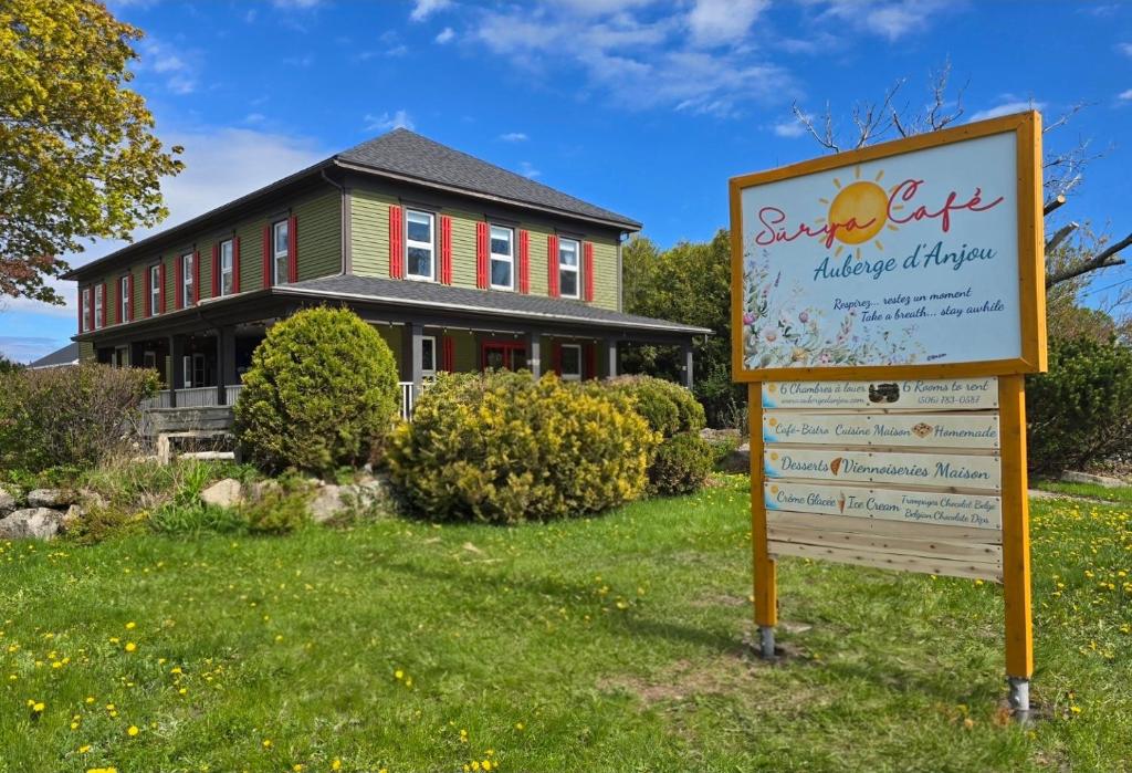 a sign in front of a house with a building at Auberge d'Anjou-Sūrya Café in Petit Rocher
