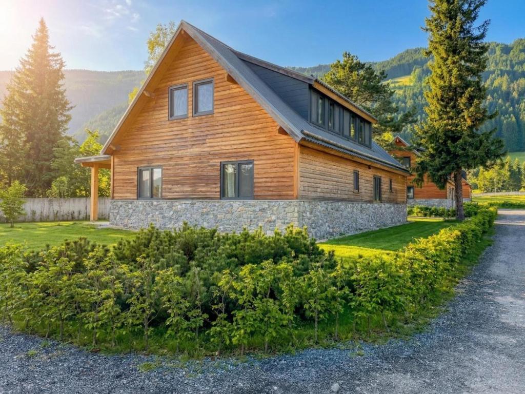 a large wooden house with a stone wall at Alpenchalet Kärntnerglück in Afritz