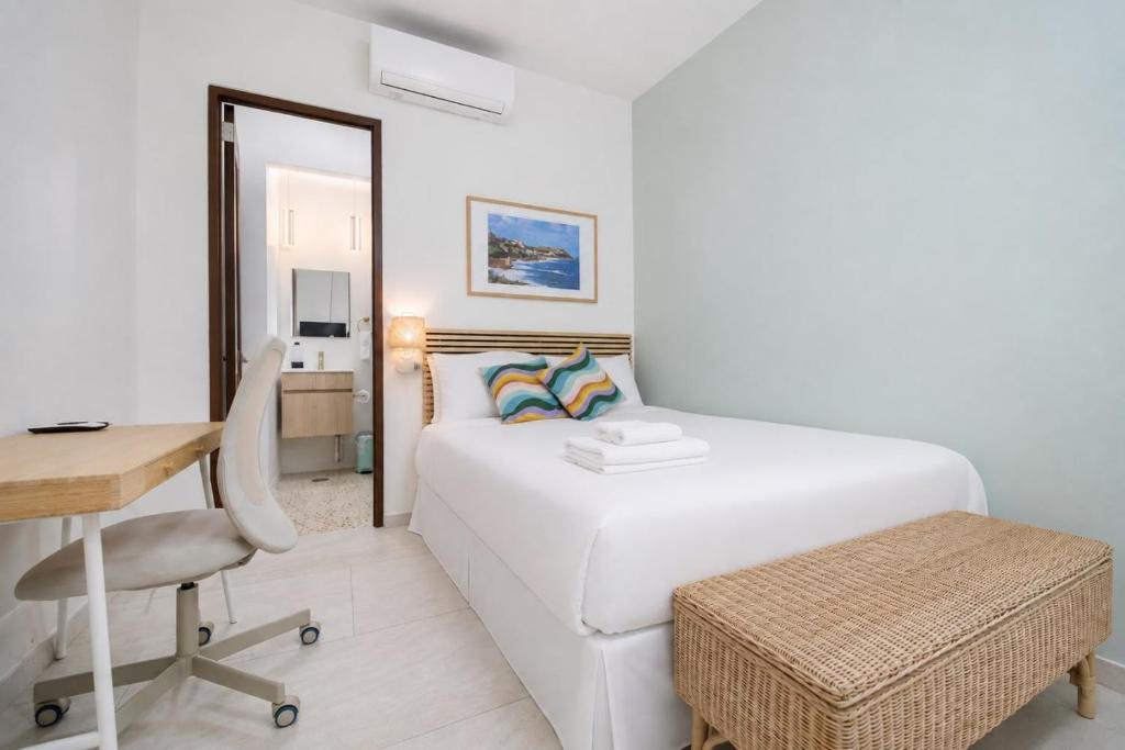 a white bedroom with a bed and a desk and a chair at Room 14: Chill City Veranda Near Miramar in San Juan