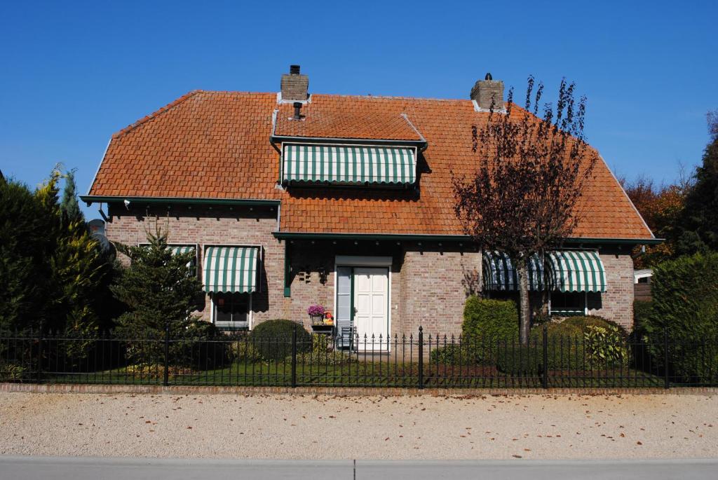 une maison avec un toit rouge et une clôture noire dans l'établissement Elegance Hamont, à Hamont