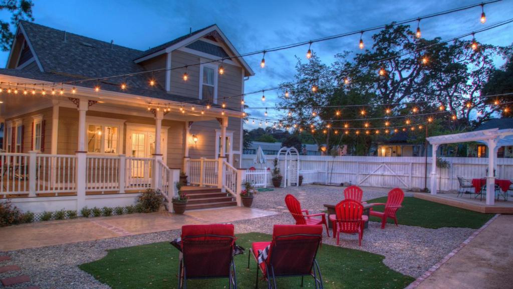 a backyard with red chairs and a table and a house at Bliss House by AvantStay in Paso Robles