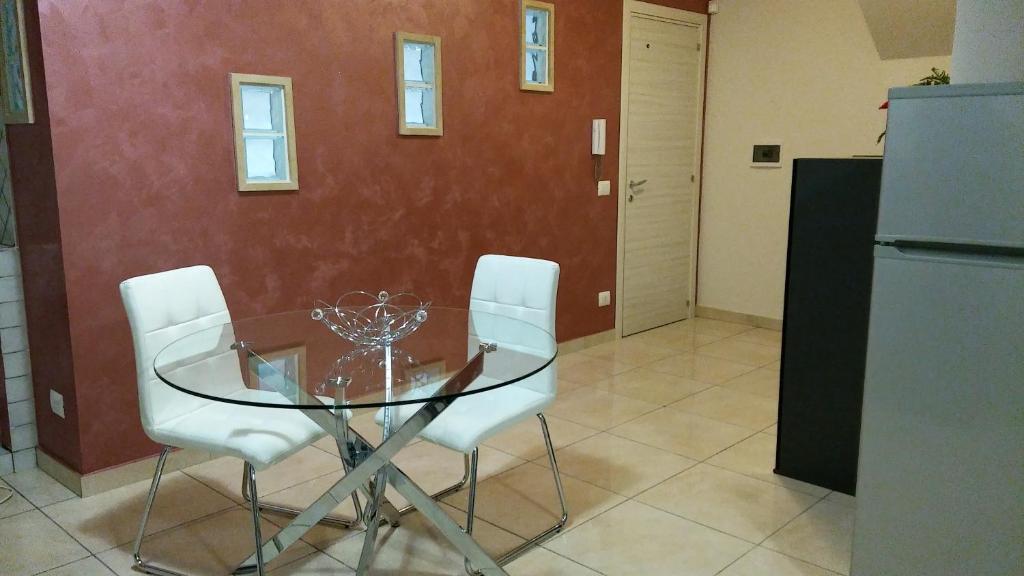 a glass table and chairs in a kitchen with a refrigerator at B&B Le Tre Gemme Junior in Lentini