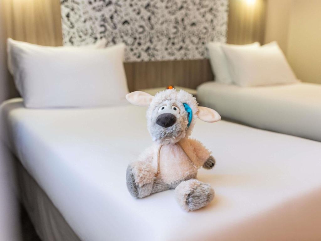 a teddy bear sitting on a bed in a hotel room at Ibis Styles Lyon Gorge de Loup Saphir in Lyon