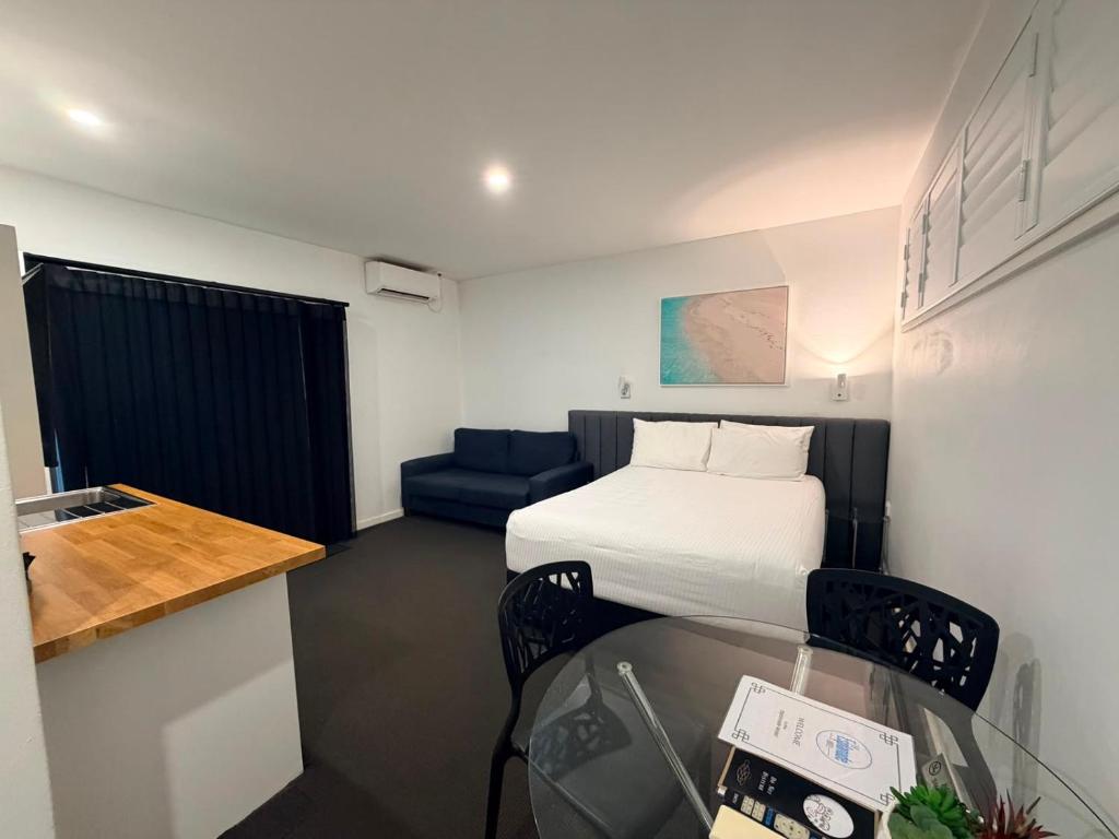 a small room with a bed and a blue couch at The Esplanade Motel in Warners Bay