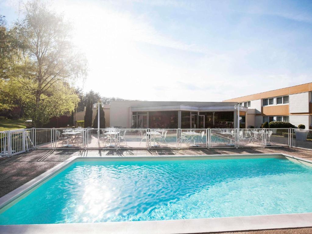 a swimming pool in front of a building at Novotel Saint Avold in Saint-Avold
