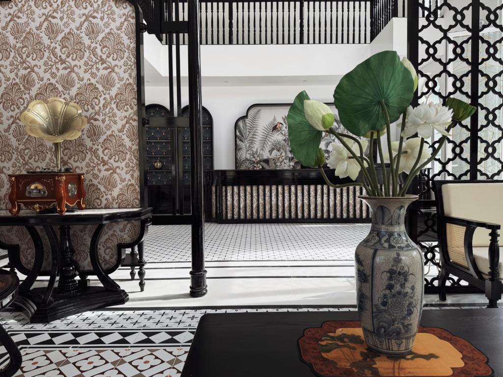 a vase with flowers on a table in a room at Celine Privé - Dalat Hotel in Da Thien