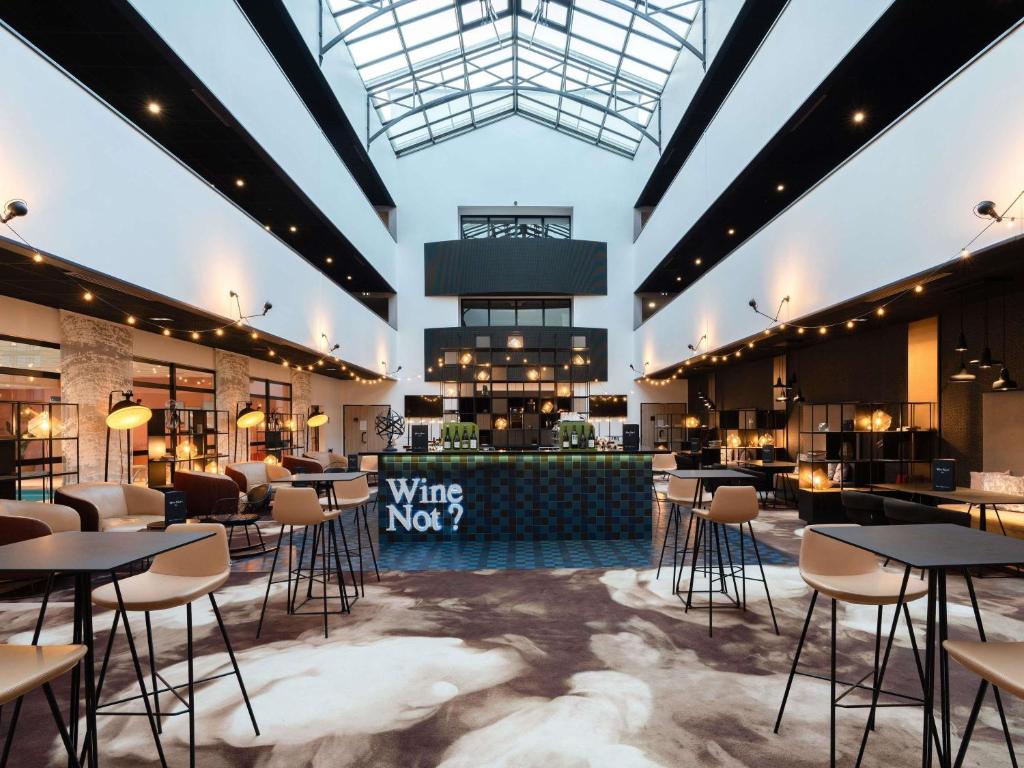 a restaurant with tables and chairs in a large room at Hotel Mercure Blois Centre in Blois