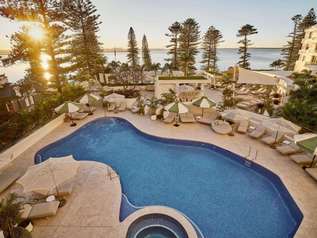 an overhead view of a swimming pool with chairs and umbrellas at The Brighton Hotel Sydney - Mgallery Collection in Sydney