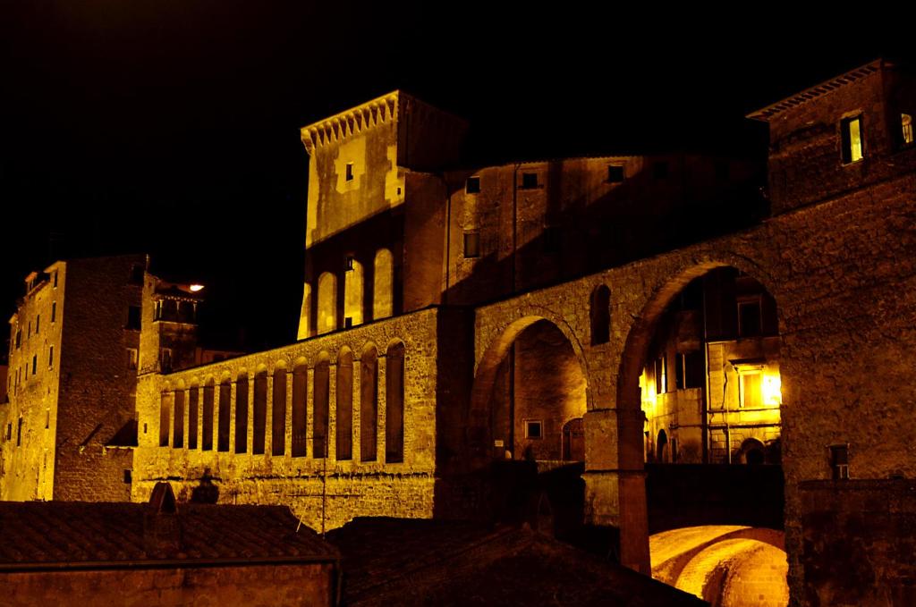 un grande edificio con torre dell'orologio di notte di Affittacamere La Magica Torre a Pitigliano