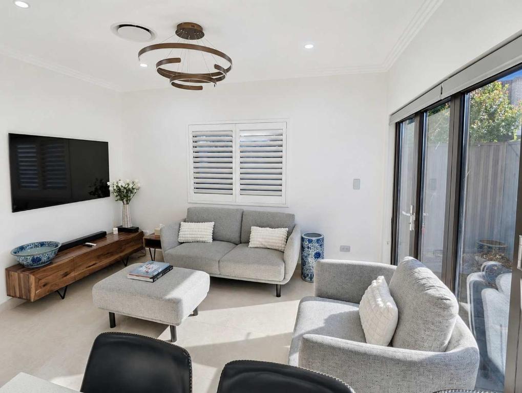 a living room with a couch and chairs and a tv at Cara Luxe Stays at Regents Park near Olympic Park and DFO in Regents Park