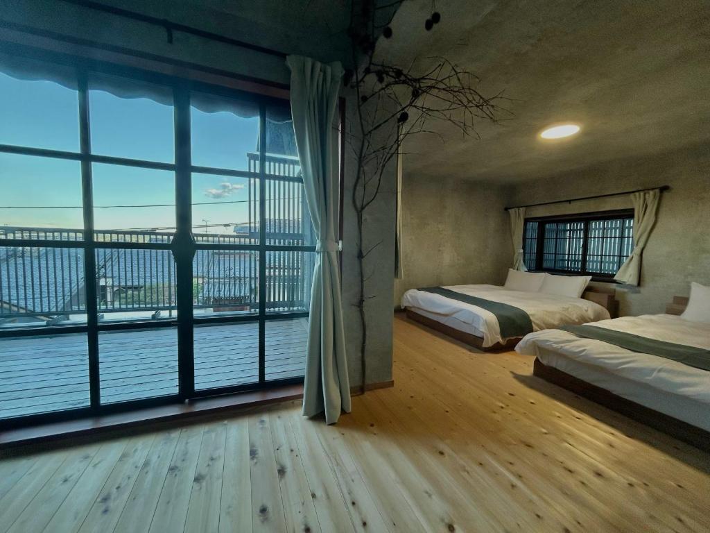 a bedroom with two beds and a large window at Deer Path Nara in Nara