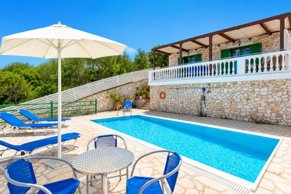 a villa with a swimming pool with chairs and an umbrella at Villa Martha in Ieromónachos