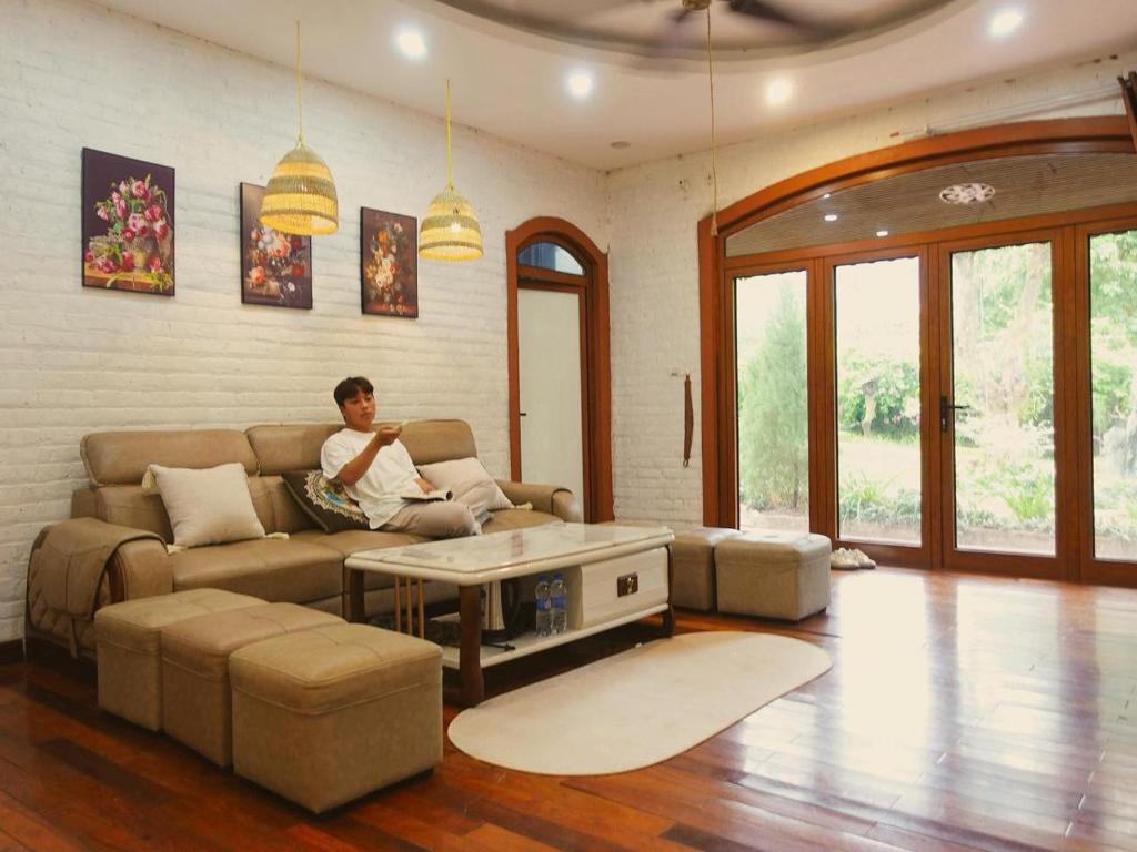 a man sitting on a couch in a living room at căn 3 ngủ in Ấp Tân Long