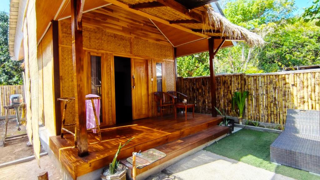 a wooden porch of a house with a patio at Dom Dom Guest House Gili Gede in Gili Gede