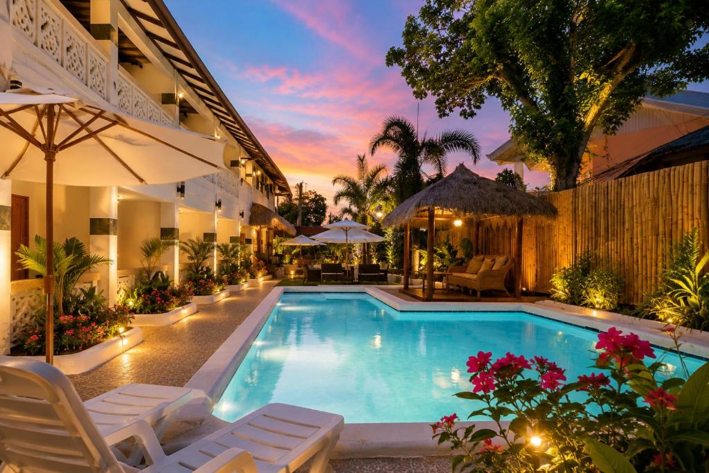 a pool at a hotel with chairs and umbrellas at Alona Garden Suites in Panglao Island