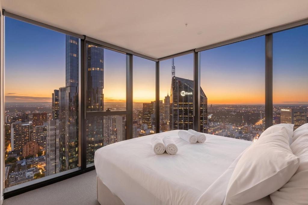 a bedroom with a white bed and large windows at Park Avenue - UNO Melbourne in Melbourne