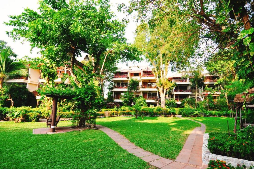 a park in front of a building with trees and a path at Birds and Bees Resort in Pattaya South