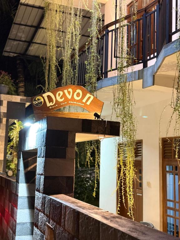 a sign on the side of a building at Devon Surf . Inn - Hiriketiya in Dickwella