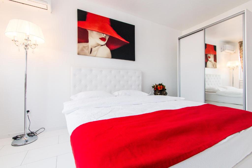 a white bedroom with a red blanket on a bed at Belvedere Danubius in Galaţi