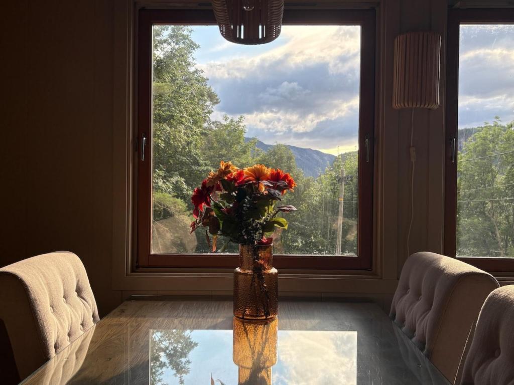 a vase of flowers on a glass table in front of a window at Hytter Brokefjell in Kviteseid
