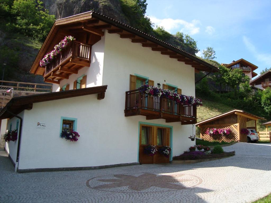 un edificio blanco con balcones y flores. en B&B El Molin en Cavalese