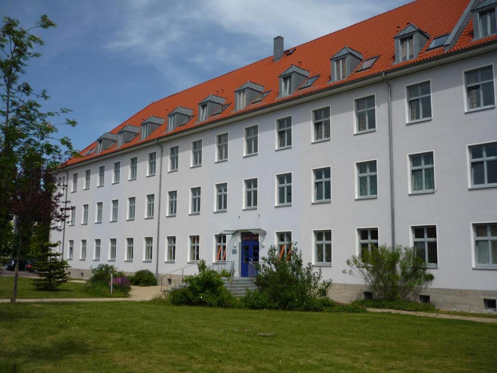 ein großes weißes Gebäude mit rotem Dach in der Unterkunft Hanse Haus Pension in Greifswald