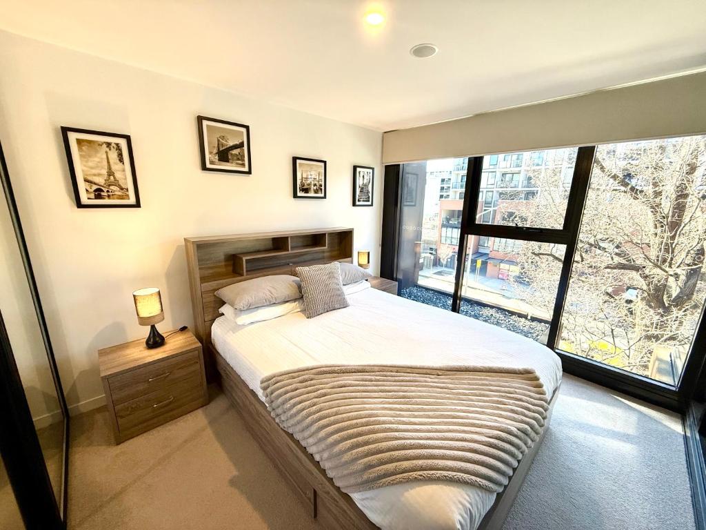 a bedroom with a large bed and a large window at Stylish Central Braddon 1 Bed, Pool, Gym, Parking in Canberra