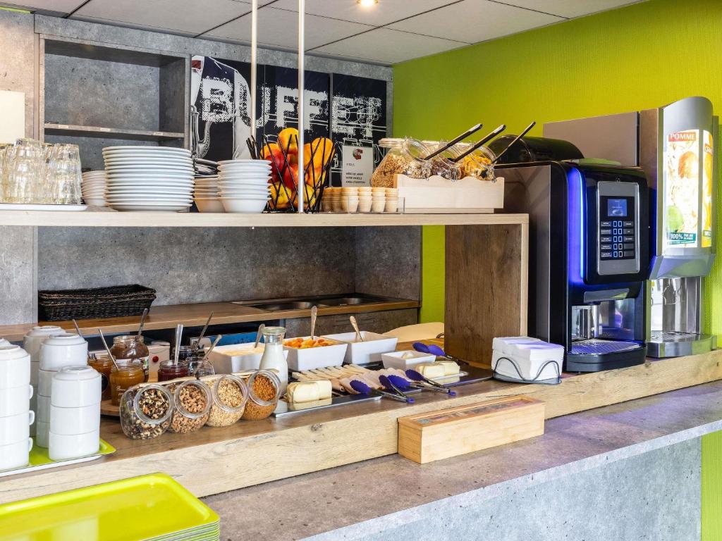 a kitchen with a counter with plates and food at ibis budget Nancy Porte Sud in Houdemont