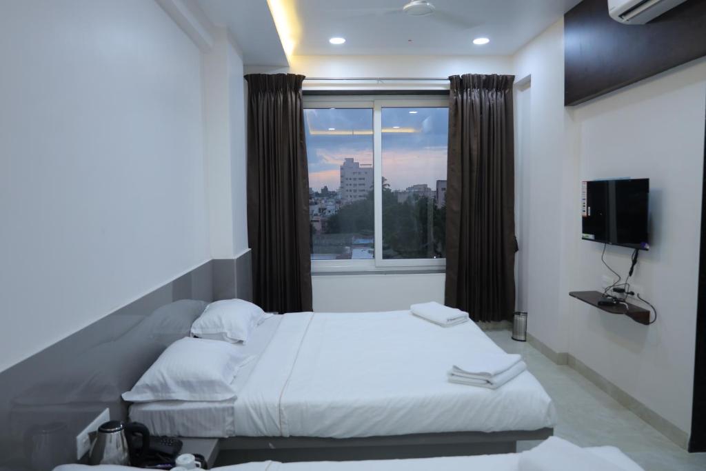 a bedroom with a bed and a large window at Hotel Shreyash in Solapur
