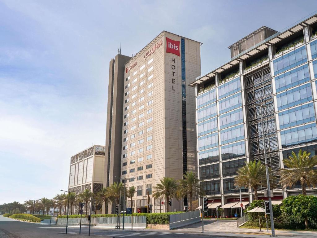 a tall building with palm trees in front of it at ibis Dubai One Central in Dubai