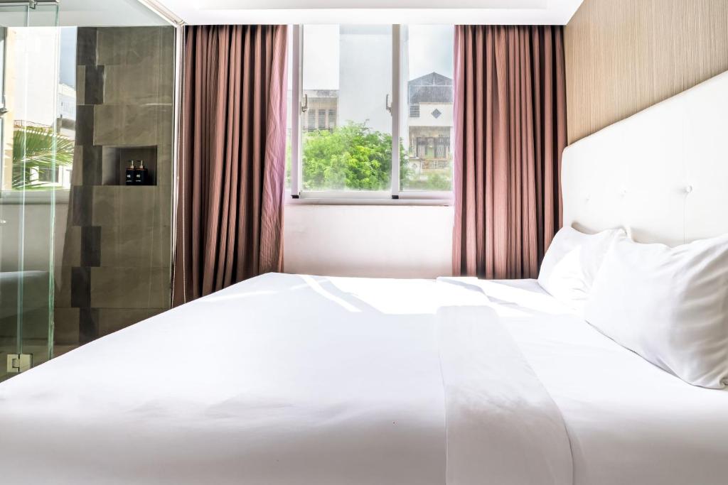 a white bed in a room with a window at Nicecy Ben Thanh Hotel in Ho Chi Minh City