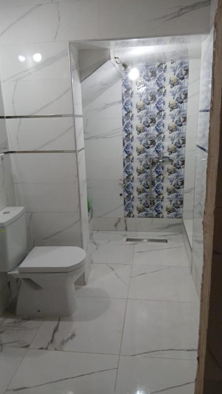 a bathroom with a toilet and a wall of wine bottles at Only in M'diq