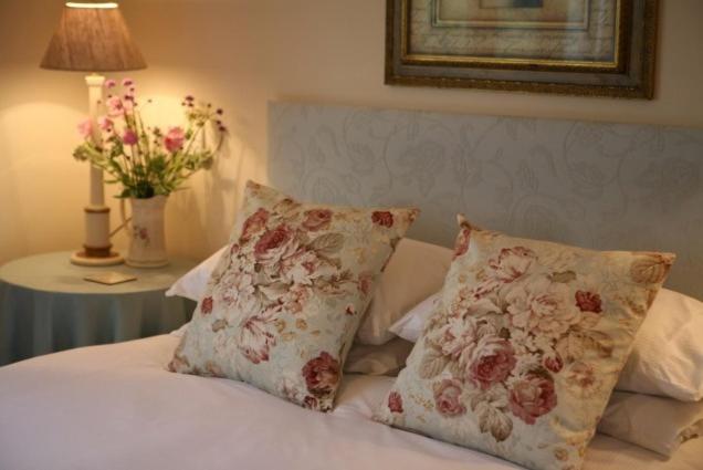 a bed with two pillows and a table with a lamp at Fox Inn in Darsham