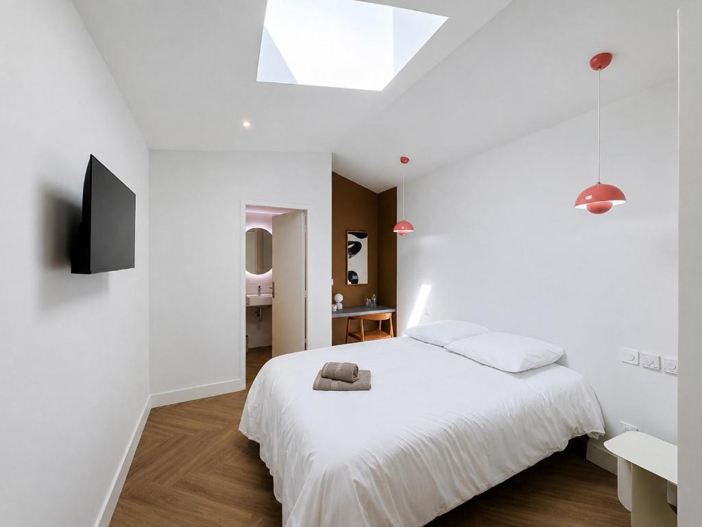 a white bedroom with a bed and a television at Maison 65 in Pierrelatte